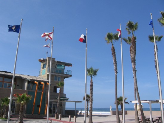 Lifeguard tower behind palm trees and flags.