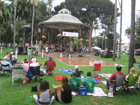 People enjoy music at the bandstand on a warm summer day.