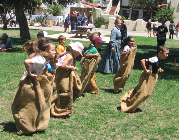 Excited kids blast off across the grass in an old-fashioned sack race!