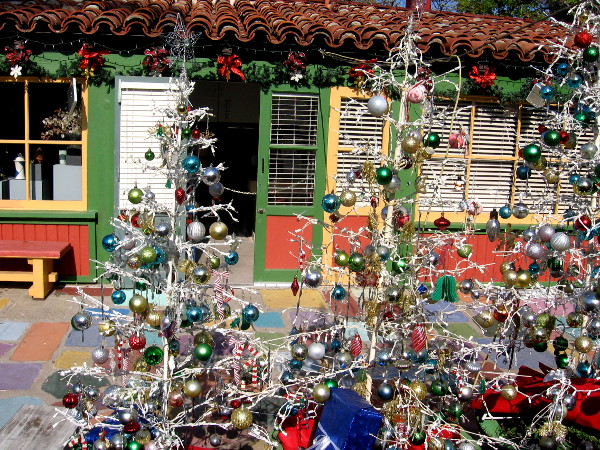 An artist studio in Spanish Village behind many very colorful Christmas trees.