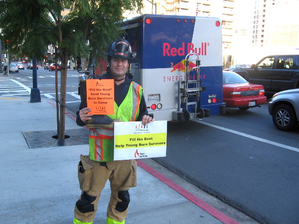 At corner of Ash and Front Street, a San Diego firefighter volunteers to collect donations to assist burn victims.