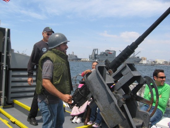 Guy enjoying the tour dons helmet and mans the Swift Boat's old 50 caliber machine gun, which is mounted over a 81mm mortar.