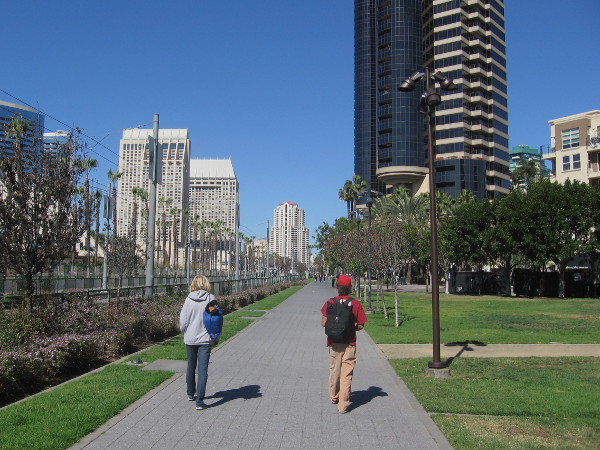 Two people walk side-by-side down the Martin Luther King Jr. Promenade in downtown San Diego.
