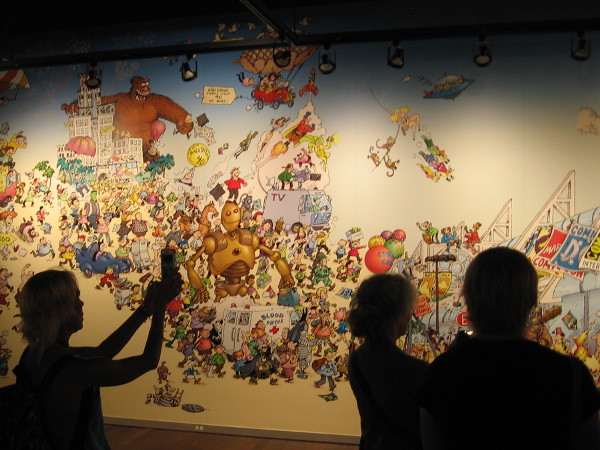 Visitors to the San Diego's Art of Comic-Con museum exhibit enjoy a huge mural from a 2008 book cover created by legendary cartoonist Sergio Aragones.