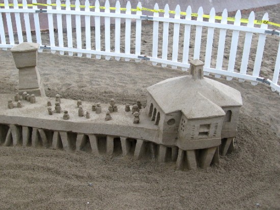 A second photo of Kirk Rademaker's sculpture. Tiny sand people stand out on a sand IB pier over the sandy Pacific Ocean!