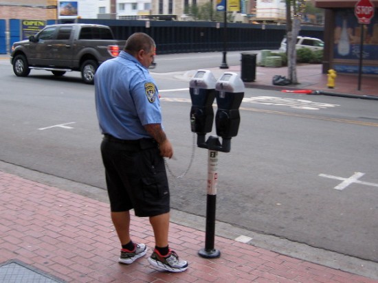 City employee checks parking meters before the streets become much busier.