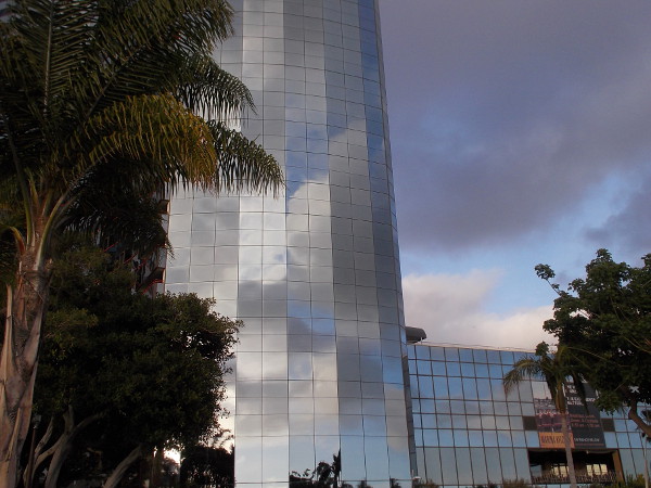 Blue sky, white and dark clouds, and fantastic patterns created by reflection off the beautiful glass building.