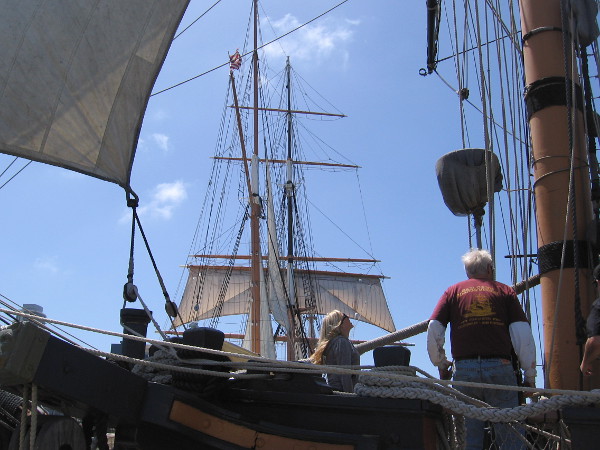 Visitors and members of the Maritime Museum of San Diego enjoy a spring Sunday aboard HMS Surprise. The Star of India's masts rise in the background.