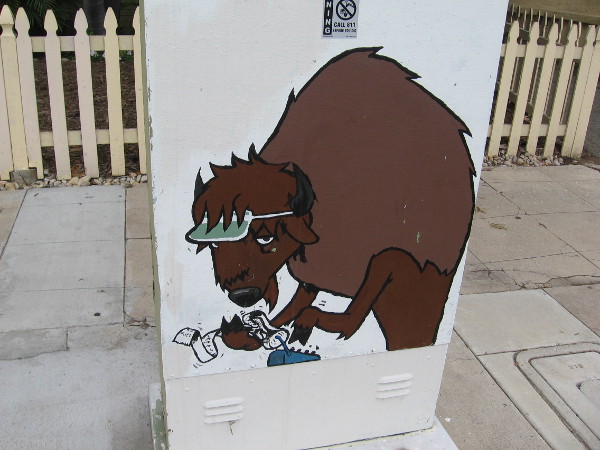 A utility box with a bit of funny street art. This tired buffalo appears to be crunching some numbers.
