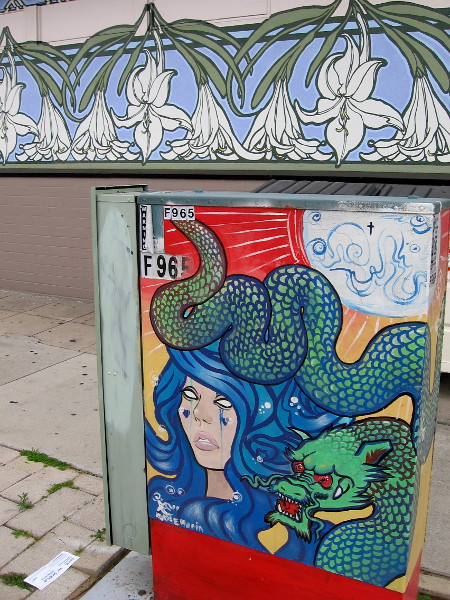 A lady and another scaly dragon on the opposite side of the box. A floral mural decorates a nearby store's wall.