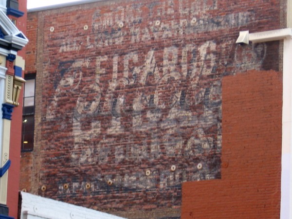 High up, painted on the old brick building's side is a fading advertisement. A glimpse of San Diego's past.