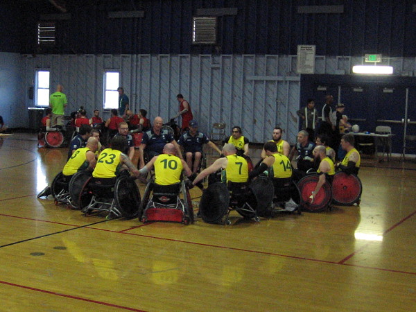 The victorious Australian quad rugby team celebrates by joining hands.