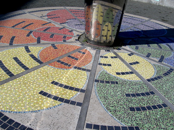 Colorful tiles radiate at the base of the rotating, wind-driven blades.