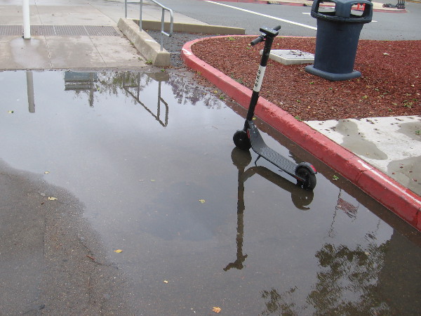 A scooter and its reflection in another puddle.