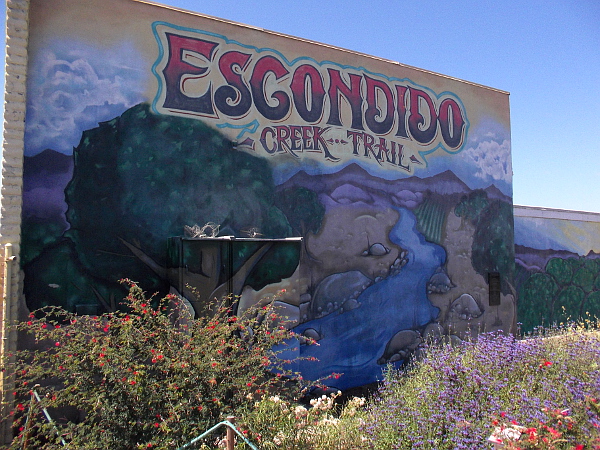 Escondido Creek Trail mural behind flowers by the popular bike and pedestrian path.