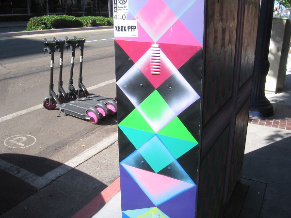 Geometric street art near scooters parked in a neat line.